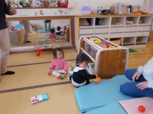 ０歳児のお友達と一緒に玩具で遊んでいます。