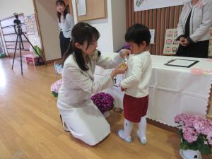 担任の先生に名札をつけてもらっています