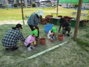 保護者と一緒に植木鉢に土を入れている子ども達