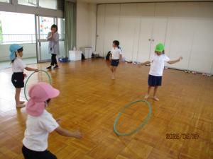 フープを友達に向かって転がしている子ども