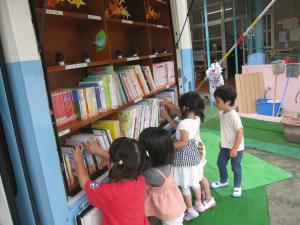移動図書のバスの中から絵本を選んでいる子ども