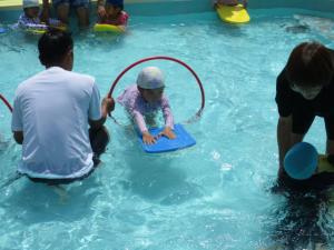 プールでフープの中をくぐっている子ども