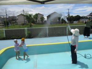 ホースのシャワーにかかる子ども