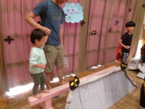 親子で平均台を渡る子ども