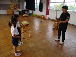 太鼓のバチの叩き方を教えてもらっている子ども達
