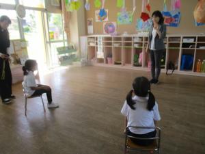 部屋で園長先生の話を聞いている子ども達