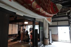 こいのぼりを飾った土間から、ほうじ茶作りワークショップが開催されているのを撮影した様子