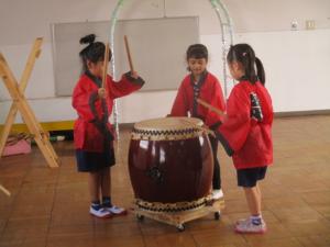 1つの和太鼓に3人で叩いている子ども達