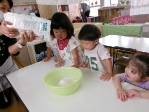 先生が粉を入れている様子を３人が見ている