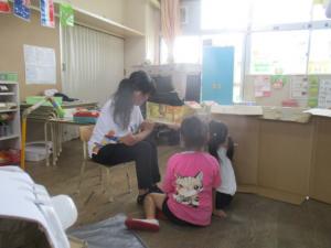 地域の方に保育室で絵本を読んでもらう子ども達
