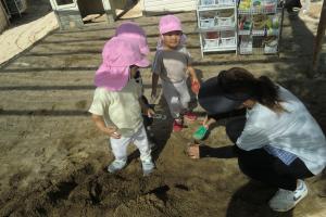 先生と砂場で遊ぶ子ども