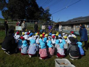 小学校の畑で地域の方のお話を聞いています