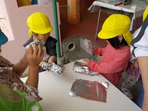 アルミホイルで芋を包む３歳児