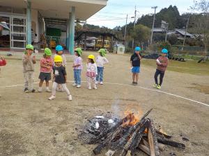 包んだ芋を火の中に入れている３歳児