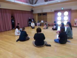 在園児1歳児親子と一緒にリトミックの先生にお話を聞いています