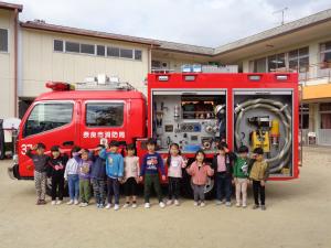 ポーズをとって消防車と写真をとる子ども