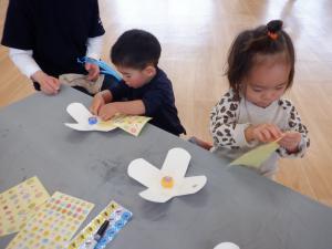 指先を使って牛乳パックの駒にシールを貼っています。