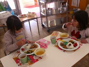 異年齢児でクリスマスメニューを食べている子ども