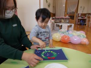 リースにシールを貼って綿棒で雪を表現しました