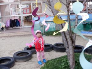 木に揺れる凧を見ている子ども。