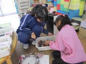 秋の実を一緒に探す園児と中学生