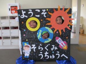 宇宙の顔はめパネルをする園児