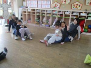 座っている先生の脚の上に座ってふれあい遊びをする園児