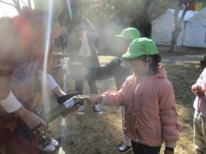 竹のコップに水を入れてもらう園児