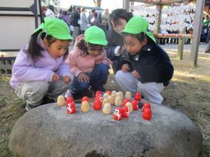 境内に至る所に置いてある小さいだるまを見る園児