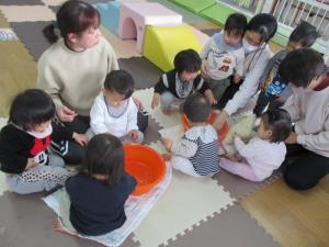 たらいに入った氷を触る子供たち
