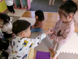 2人が丸めた新聞紙をどうぞとしている