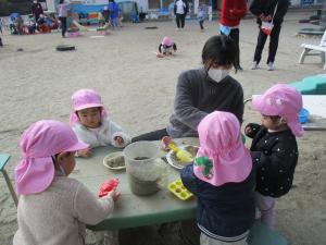 ５人で机の上で砂遊びをしている