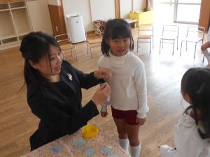 担任からコサージュをつけてもらっています