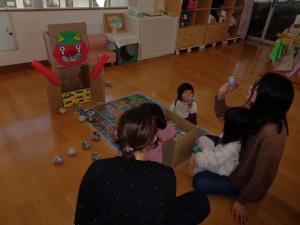 鬼の的に向かって新聞紙で作った豆を投げています