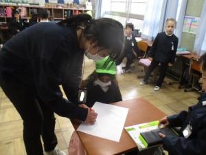 小学校の先生に丸つけをしてもらう園児