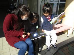 先生と絵本を見る園児