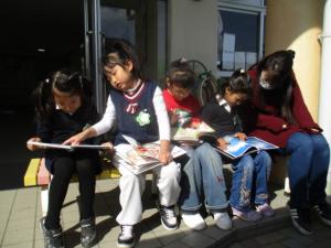 イスに座って絵本を見る園児