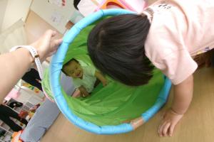 トンネルから顔をのぞかせる0歳児