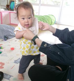 お母さんの手を持って立つ0歳児
