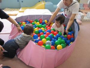 ボールプールのボールをつかんで遊んでいます