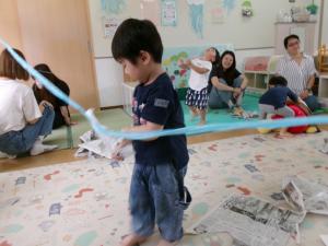 新聞紙を破って紐から取ろうとする子ども