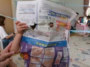 穴の開いた新聞紙から覗いている子ども