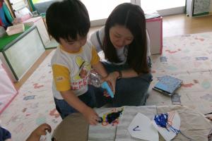 絵をかいたコーヒーフィルターに霧吹きをかける子ども