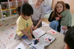 絵をかいたコーヒーフィルターに霧吹きをかける子ども