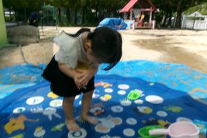 おなかで支えて色水ポンプを押そうとする子ども