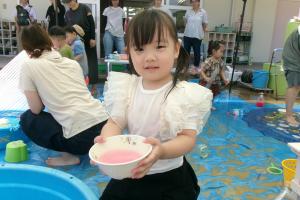 色水の入った器を持つ子ども