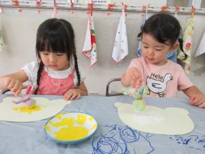 2人の子どもがたんぽを使って絵を描いています。