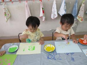 2人の子どもがタンポを持って絵を描いています。