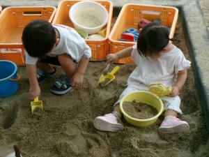 園庭で砂場遊びをしている兄弟