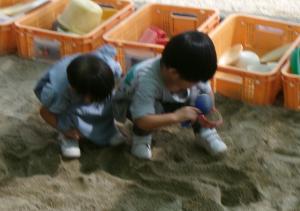 砂場で遊んでい兄をのぞき込んで見ている妹